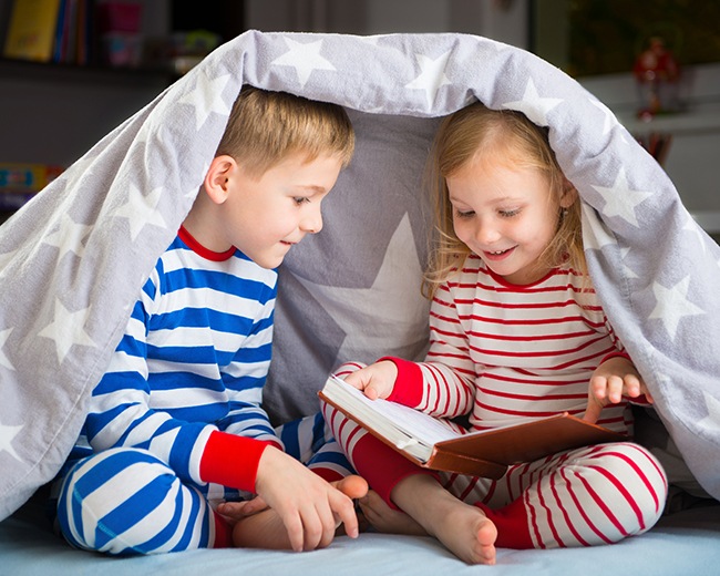two kids under a blanket reading