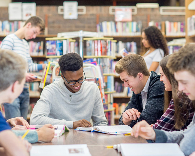 group of teens talking around a table in the library