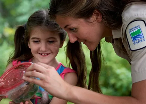 Ontario Parks Ranger showing girl a container