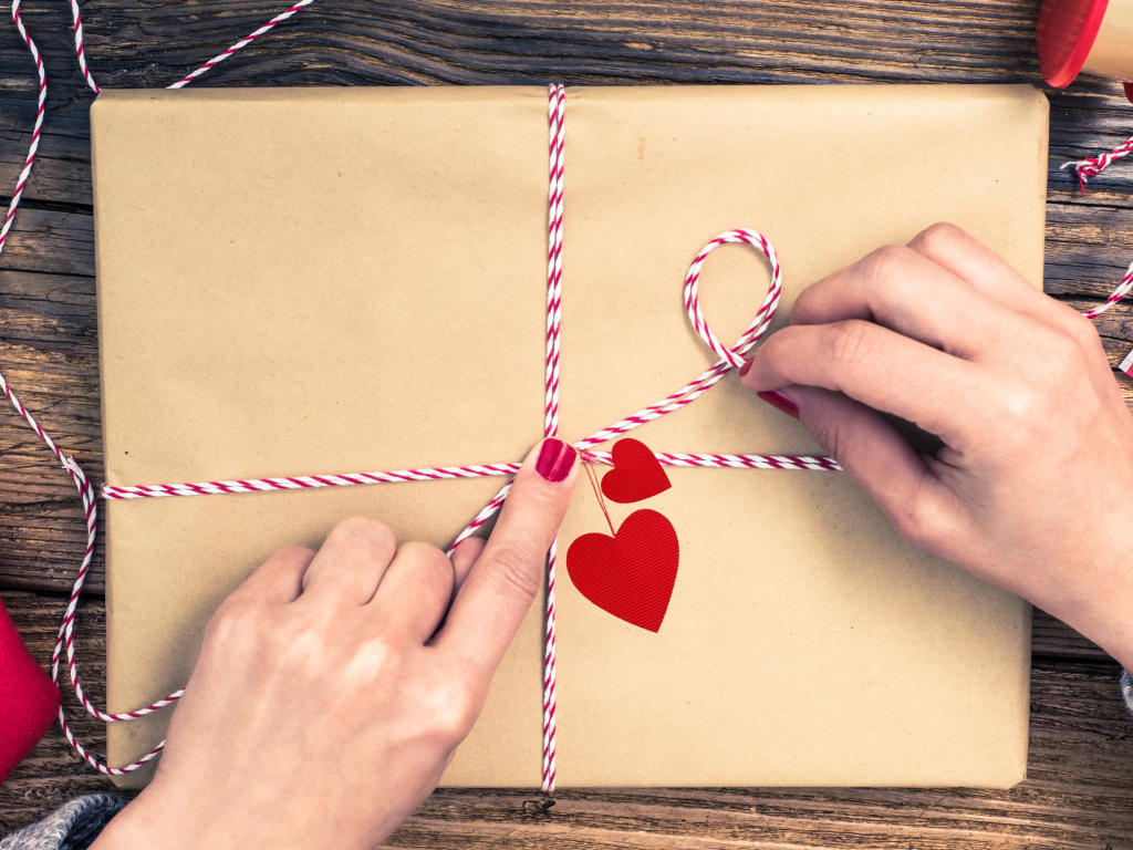 A book wrapped in brown paper and a ribbon with hearts attached