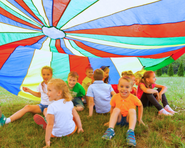 kids playing under a big colourful parachute